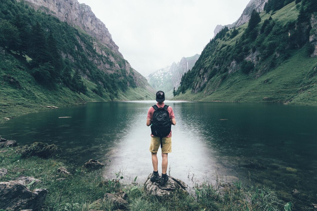 rear-view-man-standing-by-lake-mountains_1048944-16962383